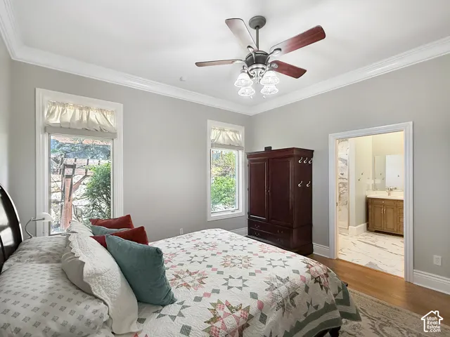 Primary bedroom with crown molding, hardwood flooring and ceiling fan.