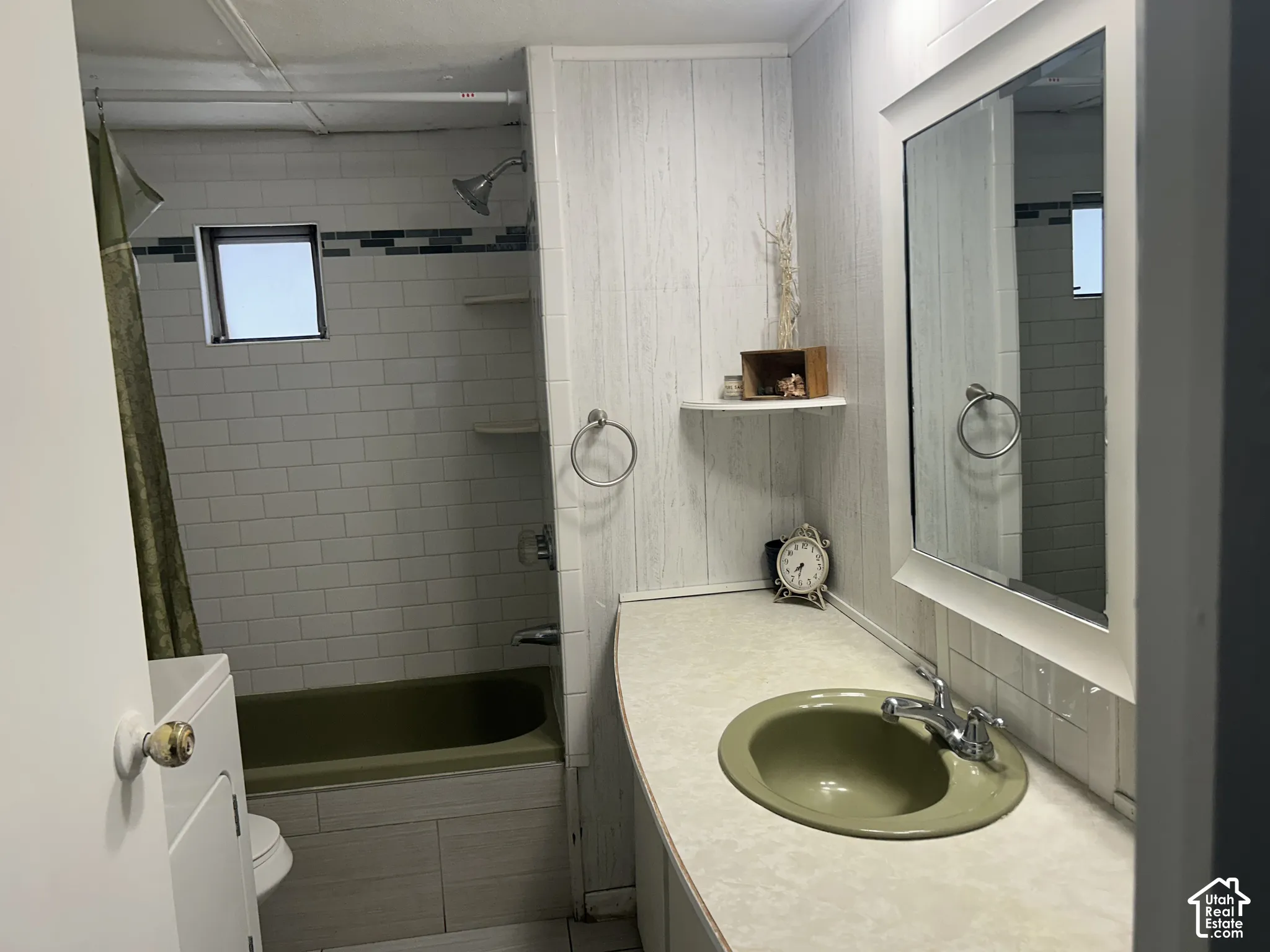Bathroom featuring a tub/shower combination, white subway tile surround with accent band, and a vanity with an integrated sink. Washer and Dryer. Storage shelf.