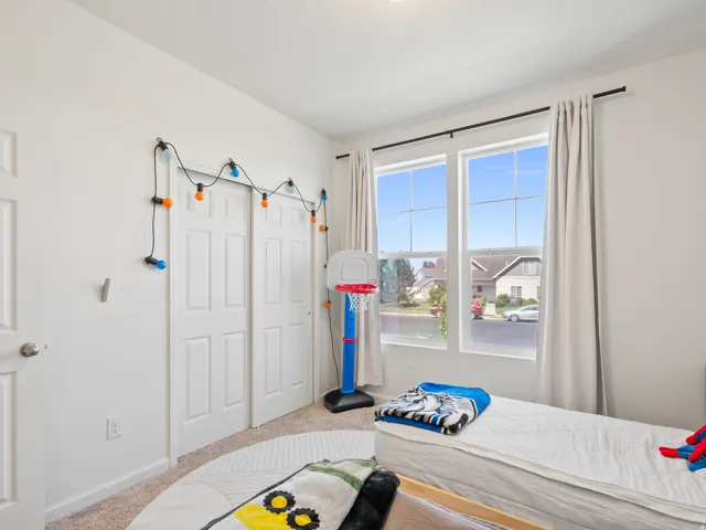 Bright room featuring two large windows with white trim, light-colored carpeting, a double-door closet with paneled doors, and white walls