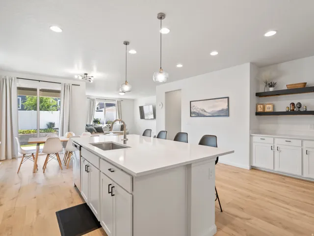 Kitchen with an expansive center island featuring a sink, white cabinetry, and a light-toned countertop