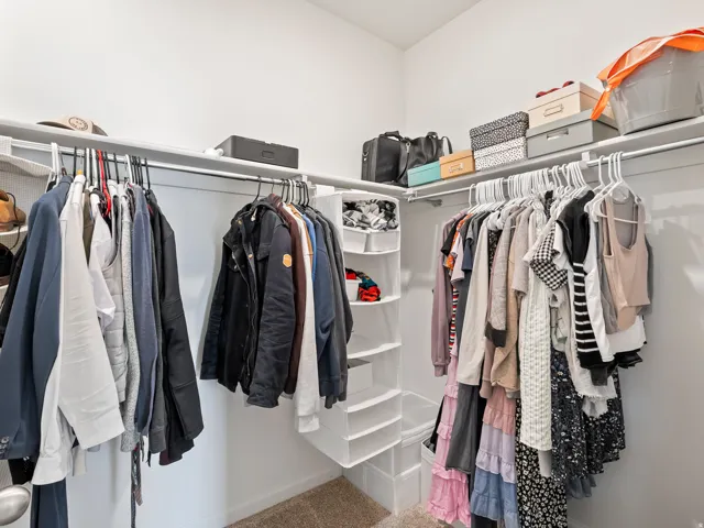Walk-in closet featuring extensive built-in shelving, multiple hanging rods, and light gray wall finishes