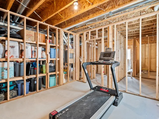 Unfinished basement space featuring exposed wood framing, concrete flooring, and visible ceiling joists