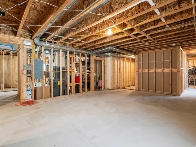 Unfinished basement featuring extensive framing, exposed ceiling joists, concrete flooring, and visible electrical conduit