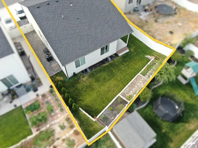Expansive rear yard featuring a manicured lawn, a privacy fence, and a dedicated garden area with raised beds