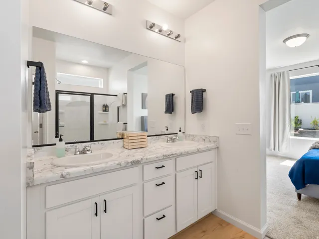 Double vanity with white cabinetry and faux marble countertops