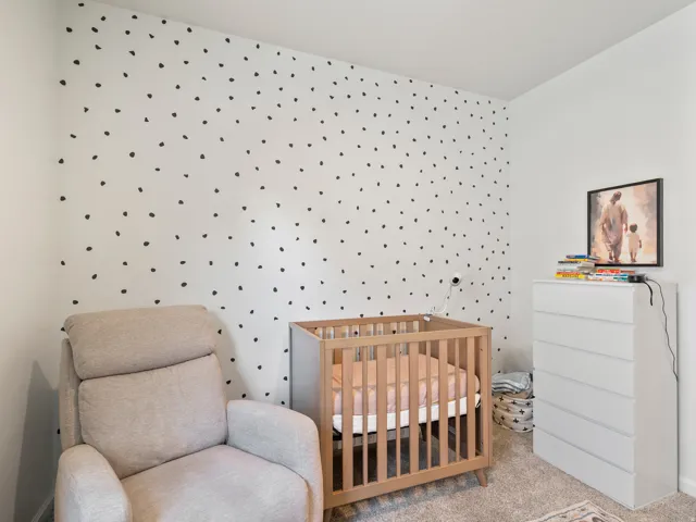 Room featuring white walls with a black polka dot accent wall and light-colored carpet flooring