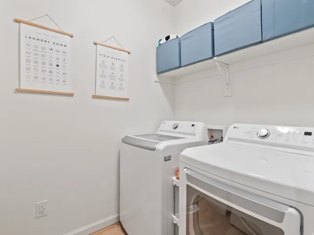 Dedicated laundry area with white walls, a built-in white shelf, and light wood-finish flooring