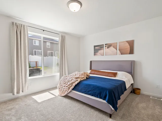 Carpeted bedroom featuring a large window, a ceiling-mounted light fixture, and white painted walls