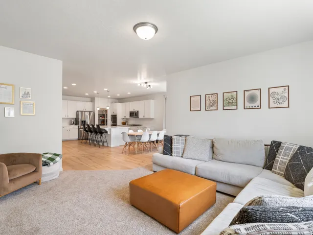 Open-concept living area featuring light-toned carpeting and smooth, light-colored walls