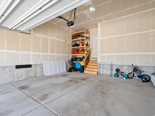 Spacious garage featuring a concrete floor, exposed drywall, and an overhead garage door opener