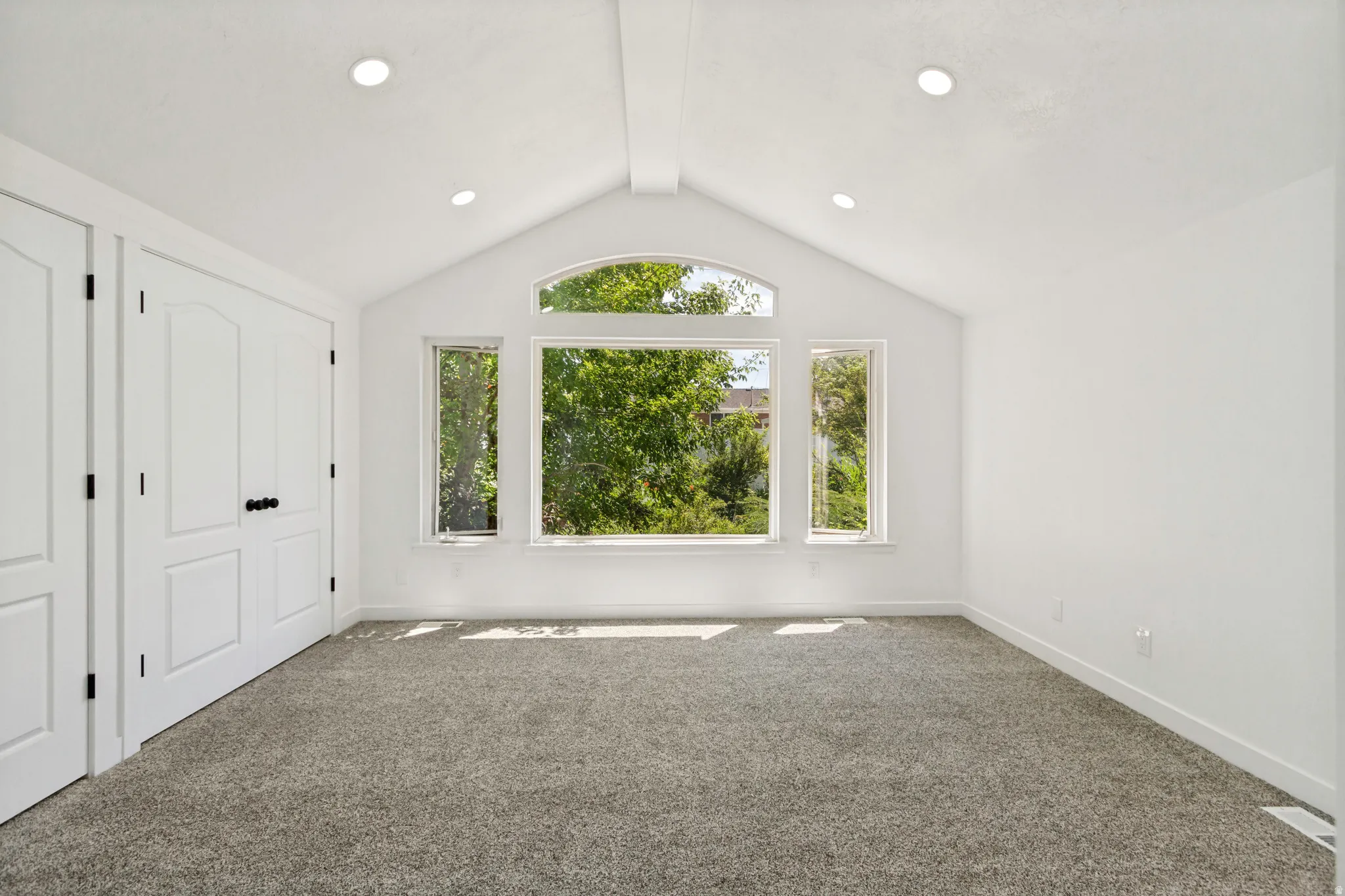 Vaulted ceiling featuring a central beam and recessed lighting