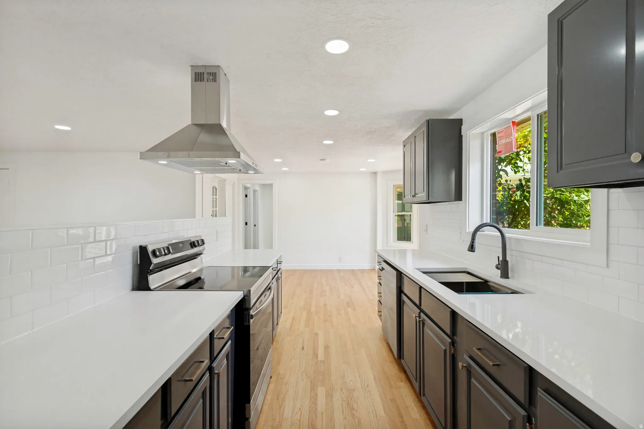 Modern kitchen featuring dark cabinetry, white countertops, and subway tile backsplash