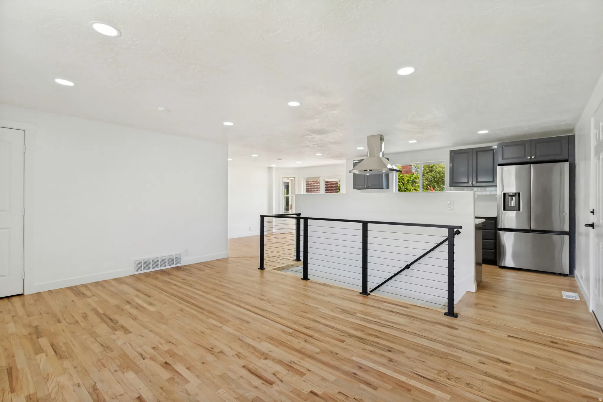 Open-concept living area featuring wood-finish flooring, recessed lighting, and a modern kitchen