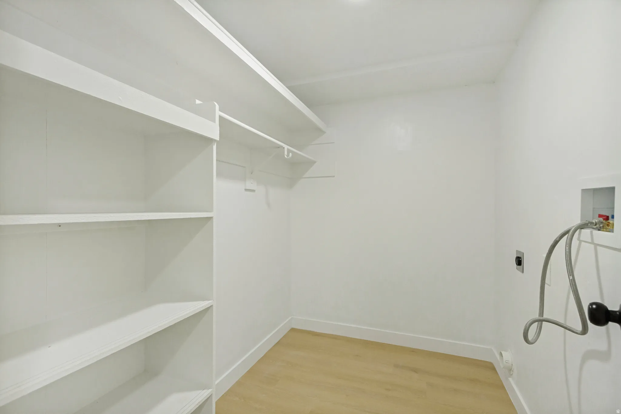 Utility room featuring wood-finish flooring, white walls, and built-in shelving