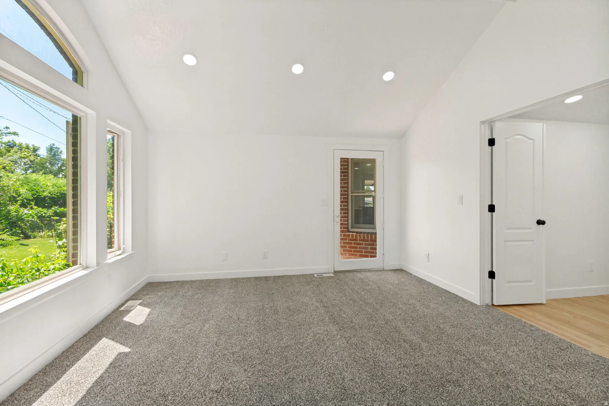 Bright room featuring a vaulted ceiling with recessed lighting