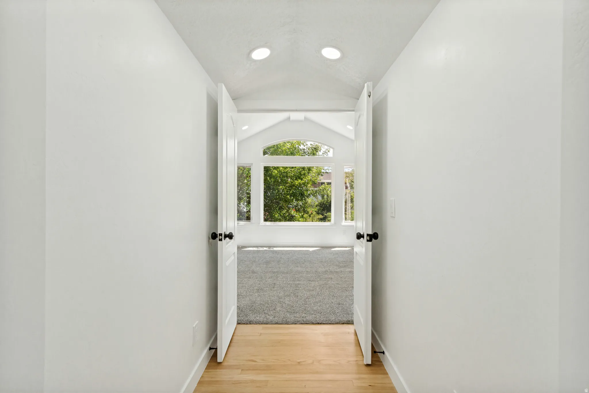 Hallway with light wood-finish flooring and recessed lighting