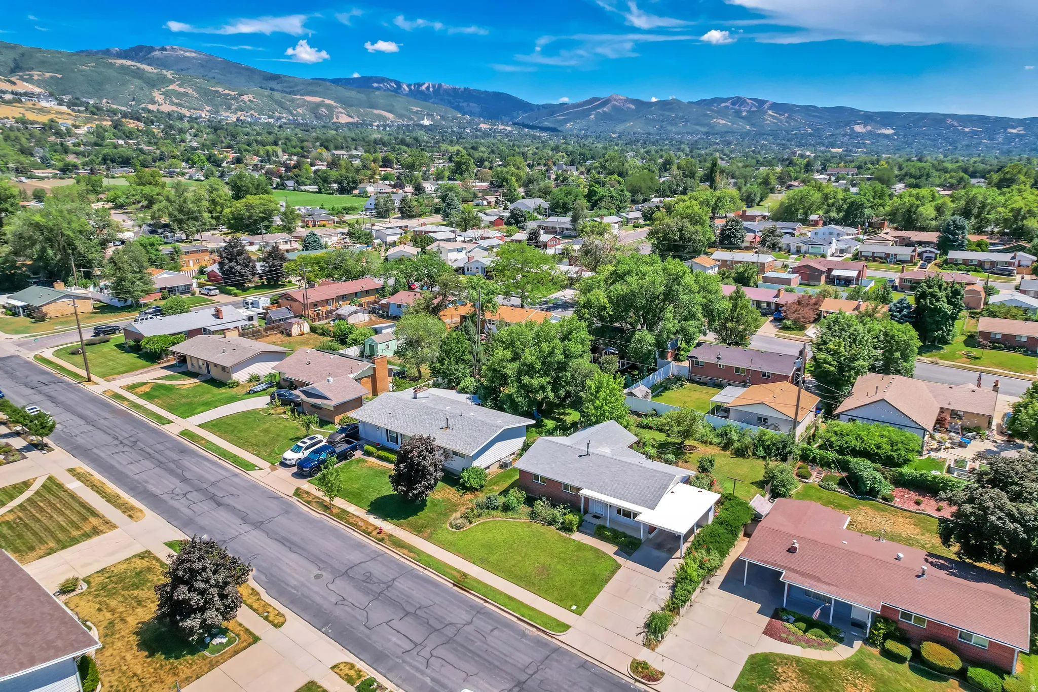 Residential neighborhood featuring mature trees and mountain scenery