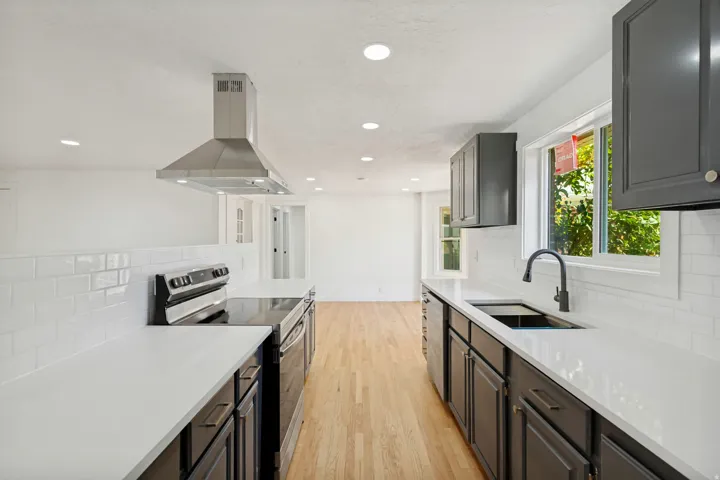 Modern kitchen featuring dark cabinetry, white countertops, and subway tile backsplash