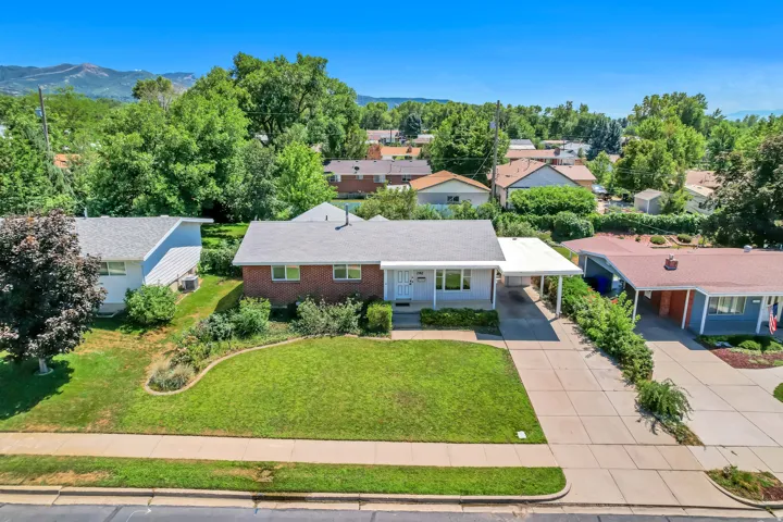 Single-story residence featuring a covered carport, concrete driveway, and a manicured front lawn with mature landscaping