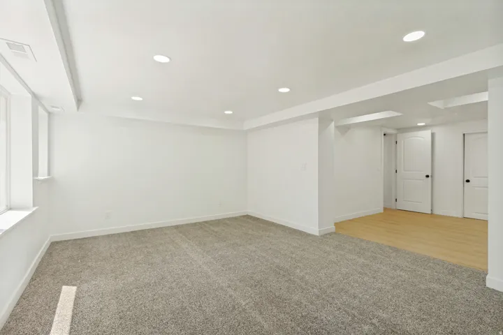 Spacious room featuring neutral carpeting, recessed ceiling lighting, and multiple windows
