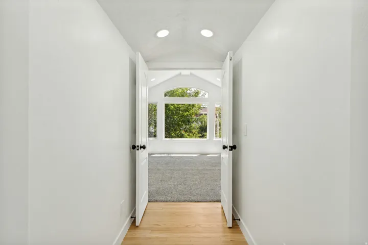 Hallway with light wood-finish flooring and recessed lighting