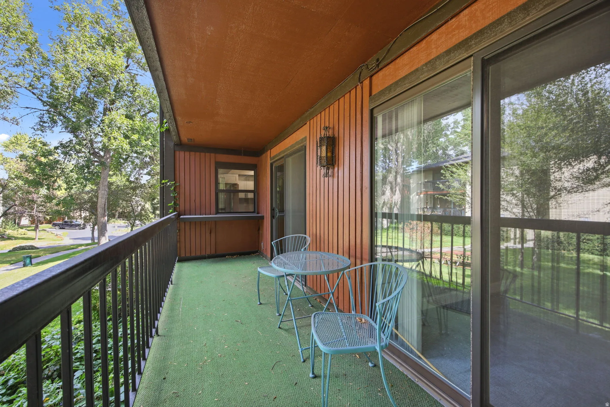 Private balcony featuring exterior wood paneling, an overhead light fixture, and sliding glass doors