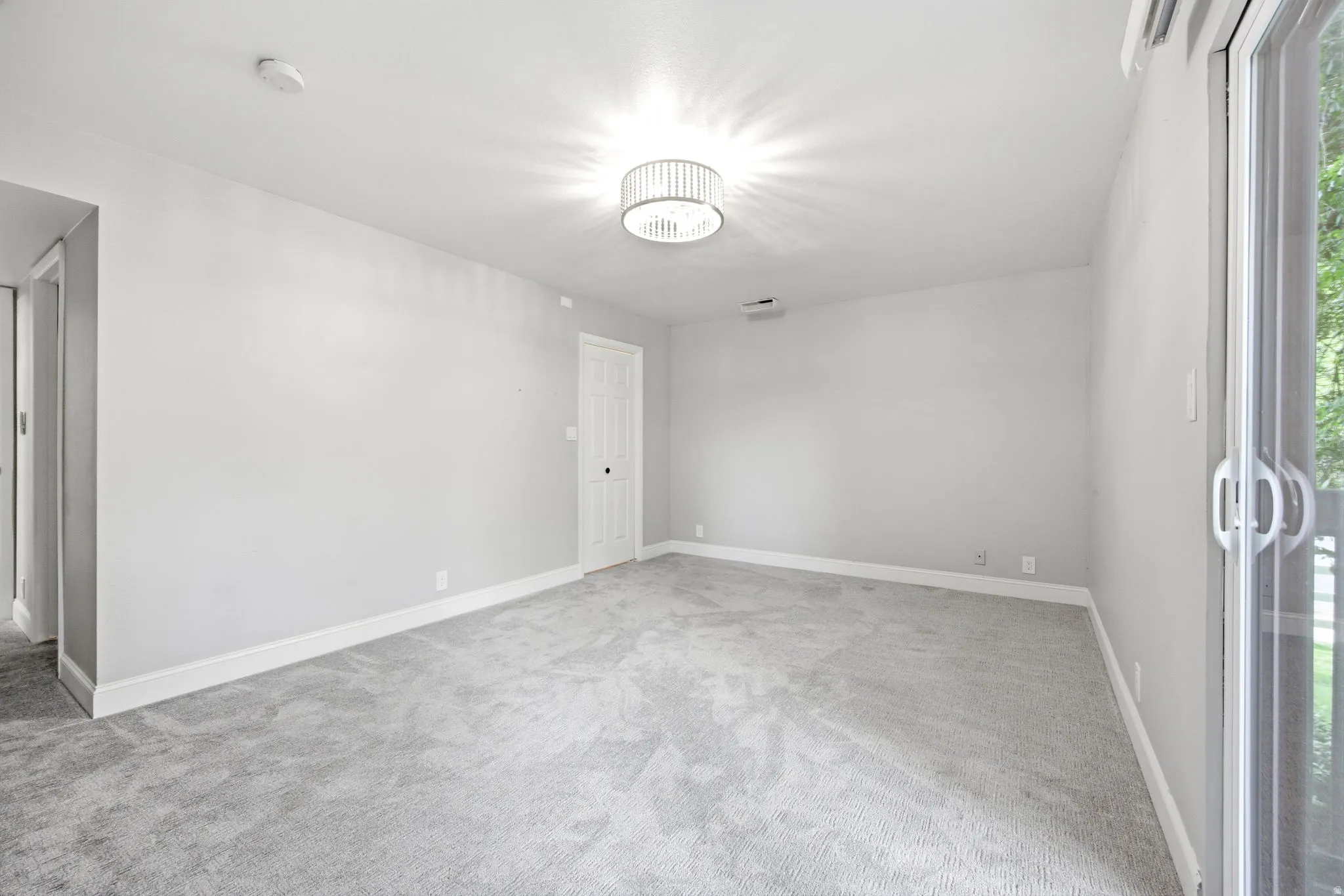 Spacious room featuring light gray carpeting, access to patio, and walk-in closet.