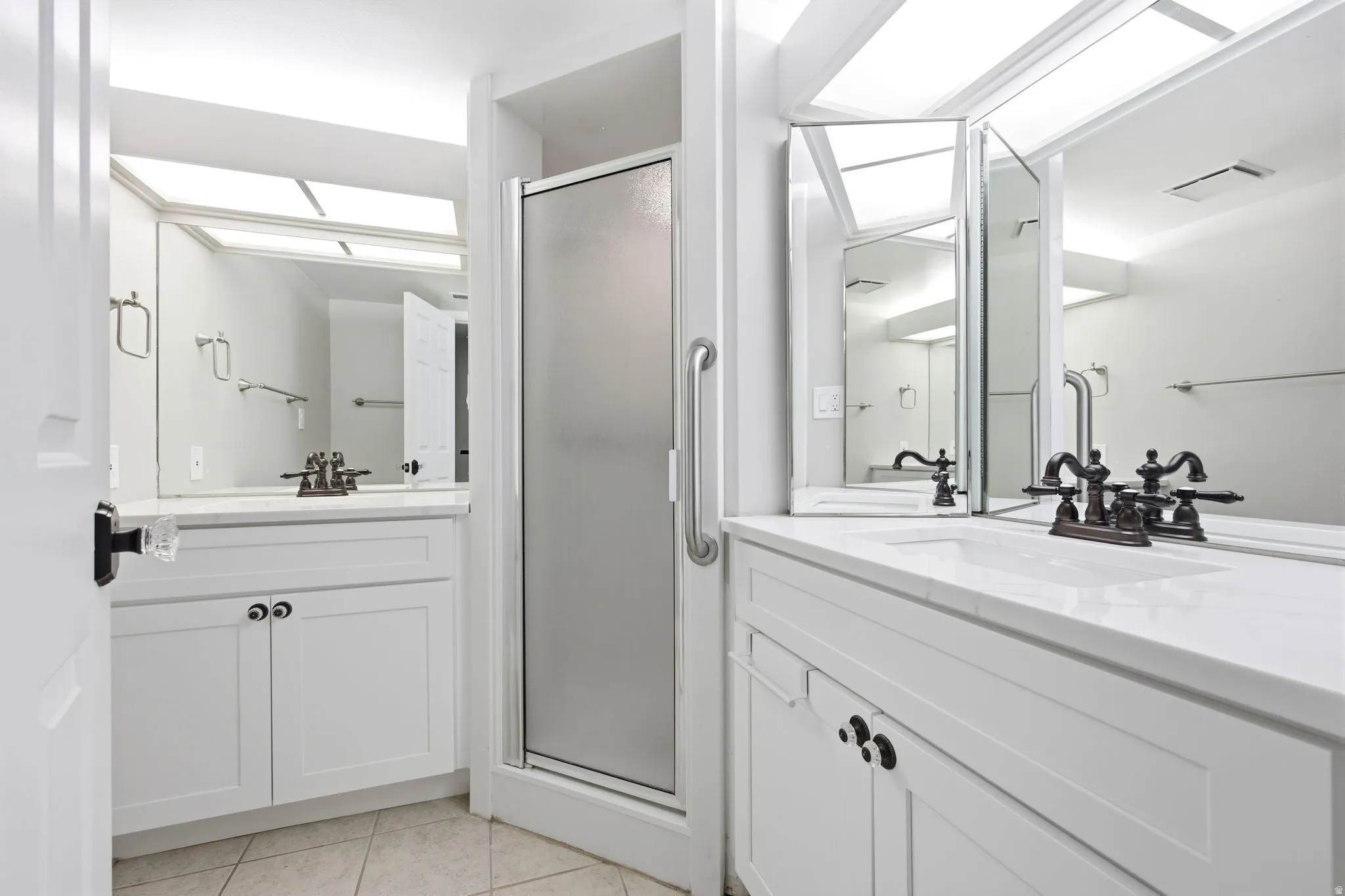 The bedroom has a private bath. Twin vanity setup featuring white cabinetry, integrated sinks, and bronze-finish faucets