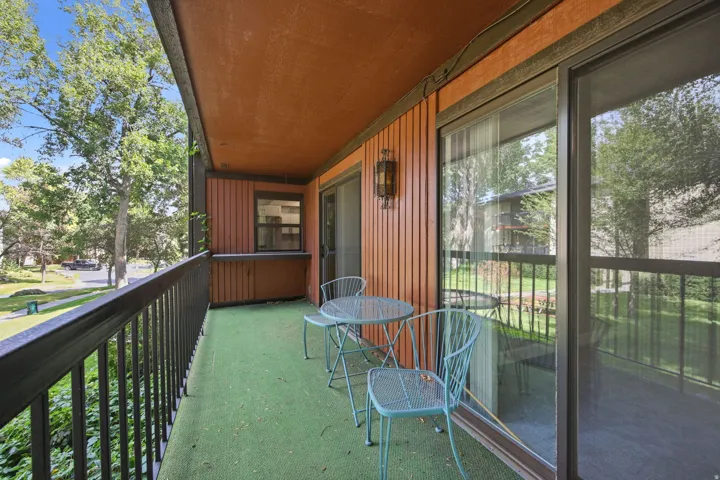 Private balcony featuring exterior wood paneling, an overhead light fixture, and sliding glass doors