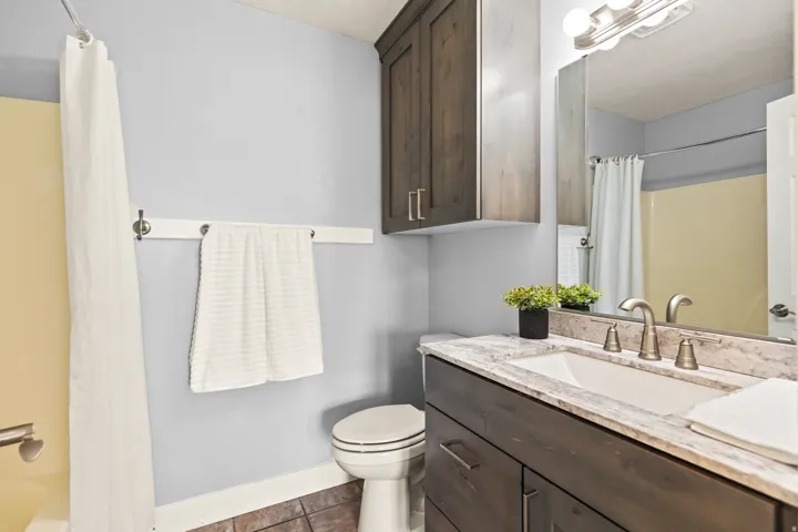 Bathroom featuring a dark wood-finish vanity with a light-toned countertop, an undermount sink, and a brushed nickel faucet