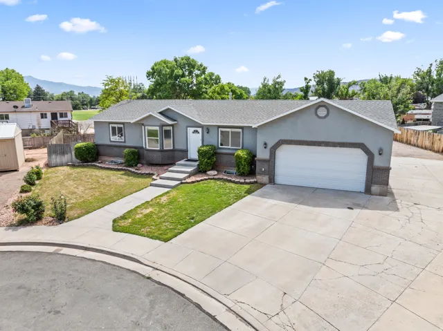 Ranch-style exterior featuring a two-tone stucco and brick facade, a two-car garage, and a concrete driveway