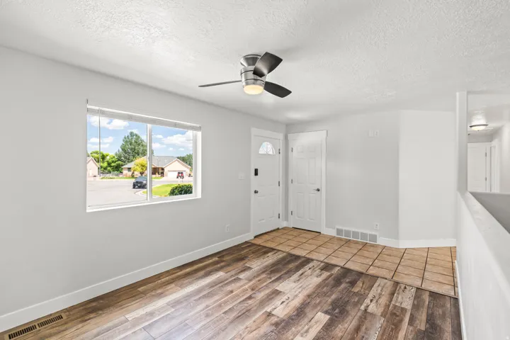 Interior space featuring wood-finish flooring, a contemporary ceiling fan with integrated lighting, and a large window