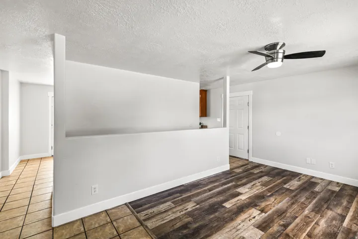 Spacious interior room featuring wood-finish flooring, a modern ceiling fan with integrated lighting, and a neutral color palette