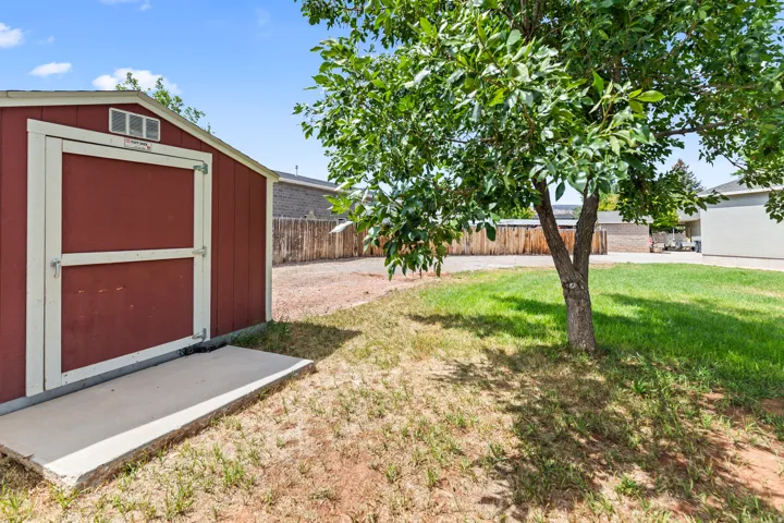 Red-sided outdoor storage shed with white trim and a concrete foundation pad