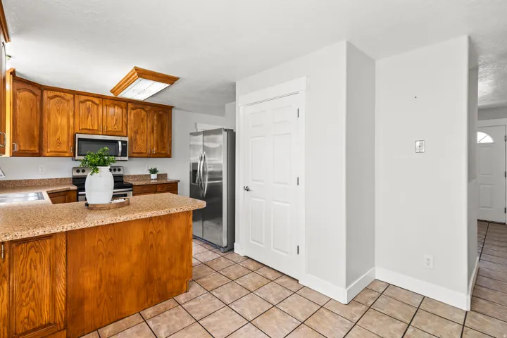 Kitchen featuring wood cabinetry, stainless steel appliances, and a central island with a stone-finish countertop