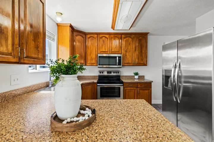 Kitchen featuring wood-finish cabinetry, speckled countertops, and stainless steel appliances