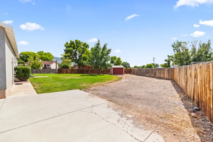 Spacious backyard featuring a concrete patio, expansive lawn area, and a large gravel section