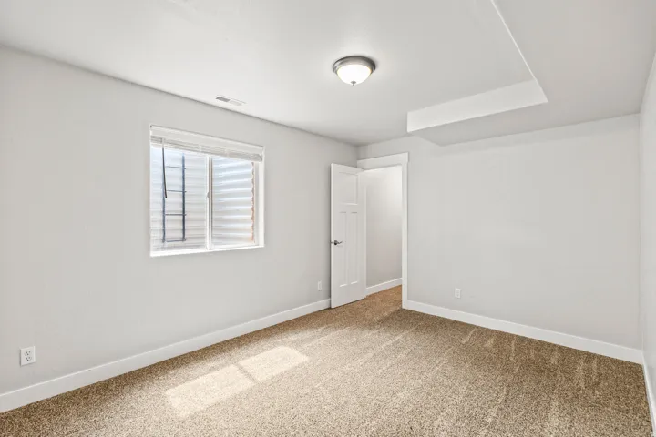 Carpeted room featuring a white interior door, a single window with blinds, and recessed ceiling elements