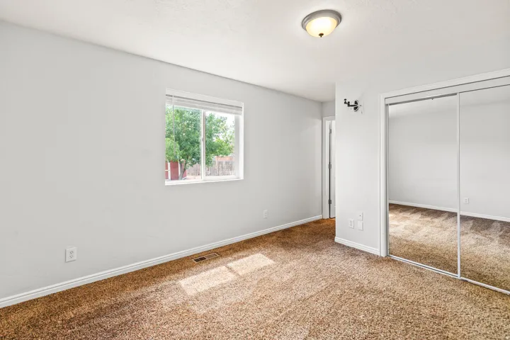 Carpeted room featuring a double-pane window, white trim, a flush mount ceiling light, and mirrored sliding closet doors
