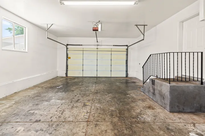 Spacious garage featuring a concrete floor, overhead lighting, and an automatic garage door opener