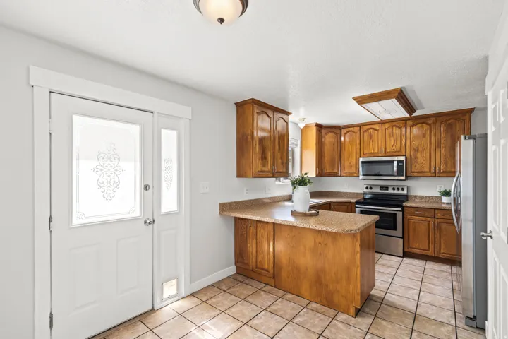 Kitchen featuring wood cabinetry, stone-finish countertops, and stainless steel appliances