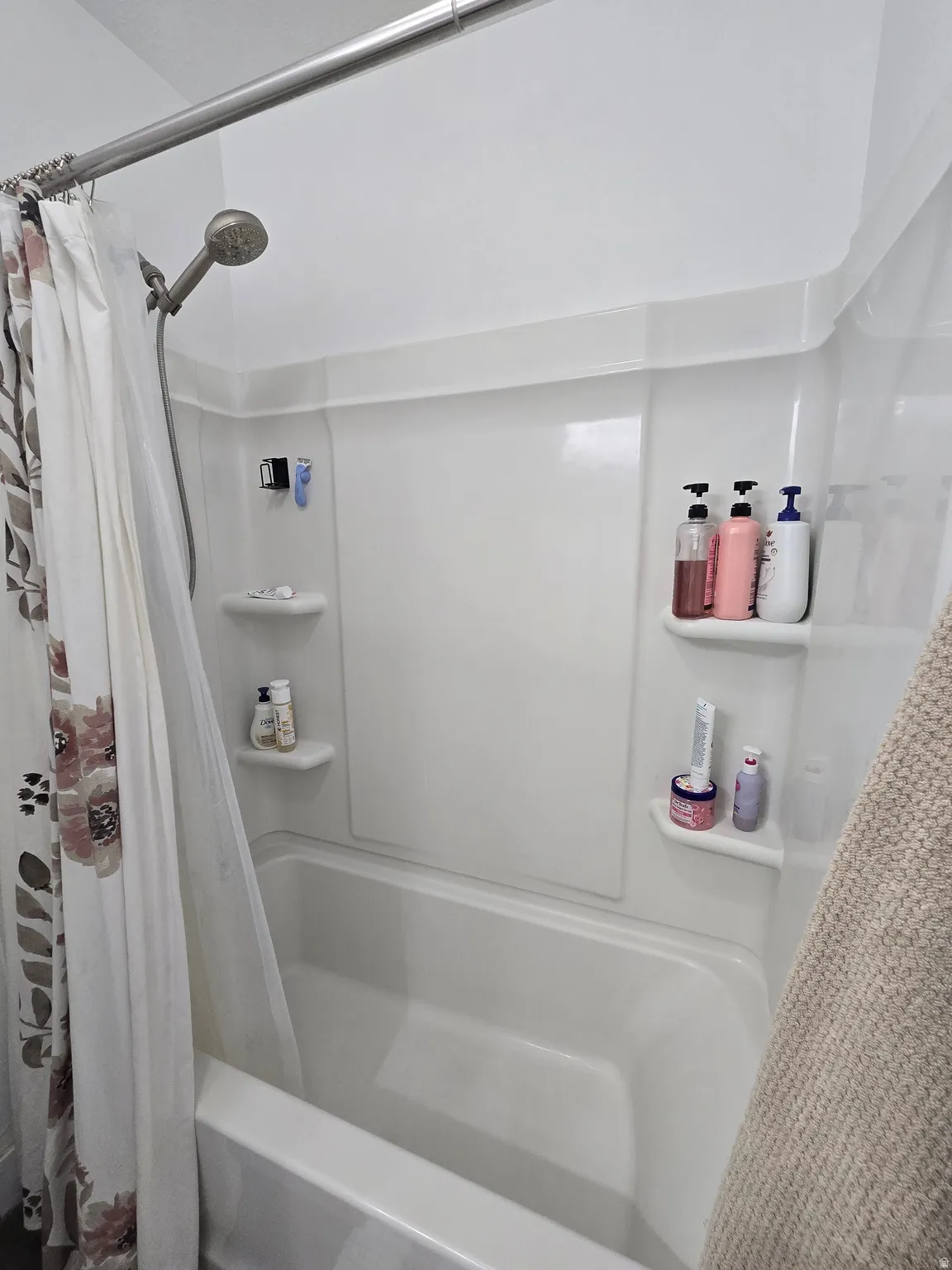 White acrylic bathtub and shower surround with integrated shelving