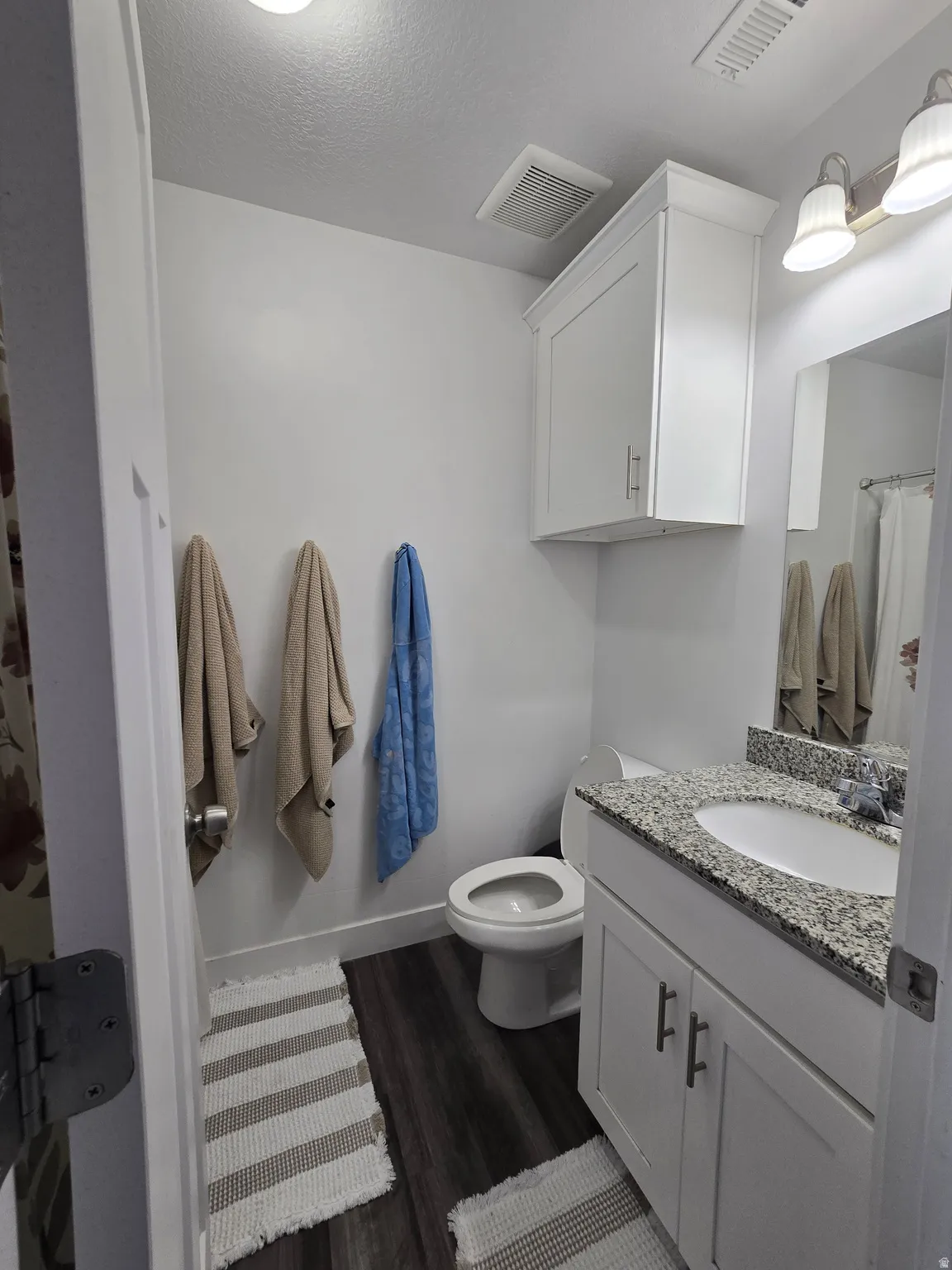 Bathroom featuring a white vanity with a granite countertop, undermount sink, and brushed nickel hardware