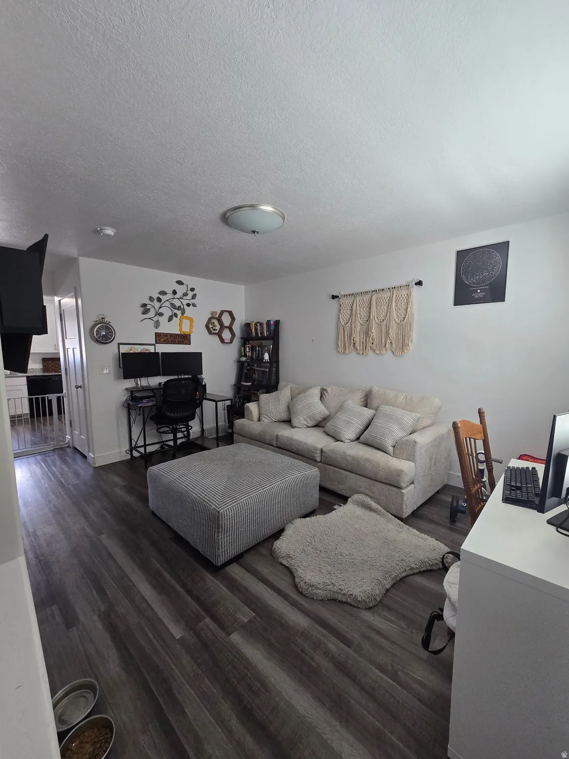 Spacious living area featuring wood-finish flooring, a wall-mounted television, and a ceiling-mounted light fixture