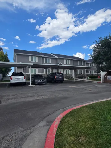 Two-story multi-unit building with light gray siding and dark roofing