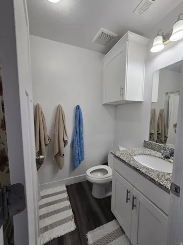 Bathroom featuring a white vanity with a granite countertop, undermount sink, and brushed nickel hardware
