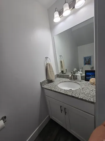 Bathroom vanity featuring a granite countertop with an undermount sink, brushed nickel faucet, and a large wall-mounted mirror