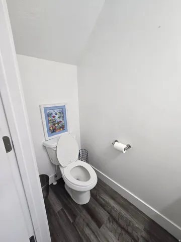 Bathroom featuring white walls, wood-finish flooring, and a white toilet