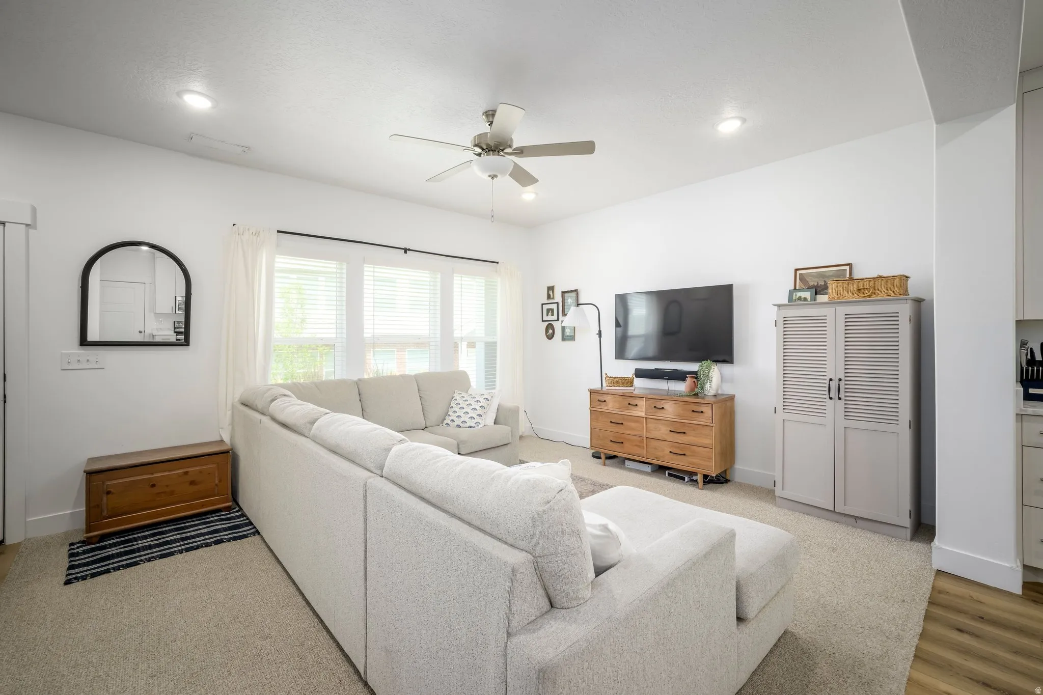 Bright living space featuring recessed lighting, a ceiling fan, and large windows with blinds