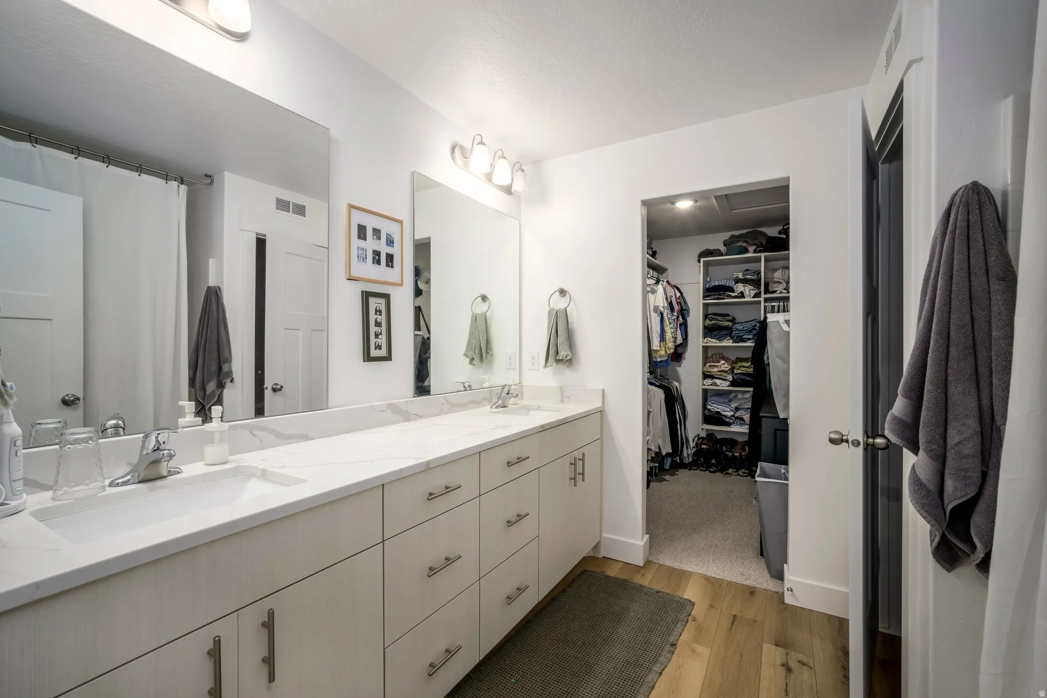 Primary Bathroom featuring a long dual vanity with light-toned cabinetry and a light-toned countertop, set against a white wall
